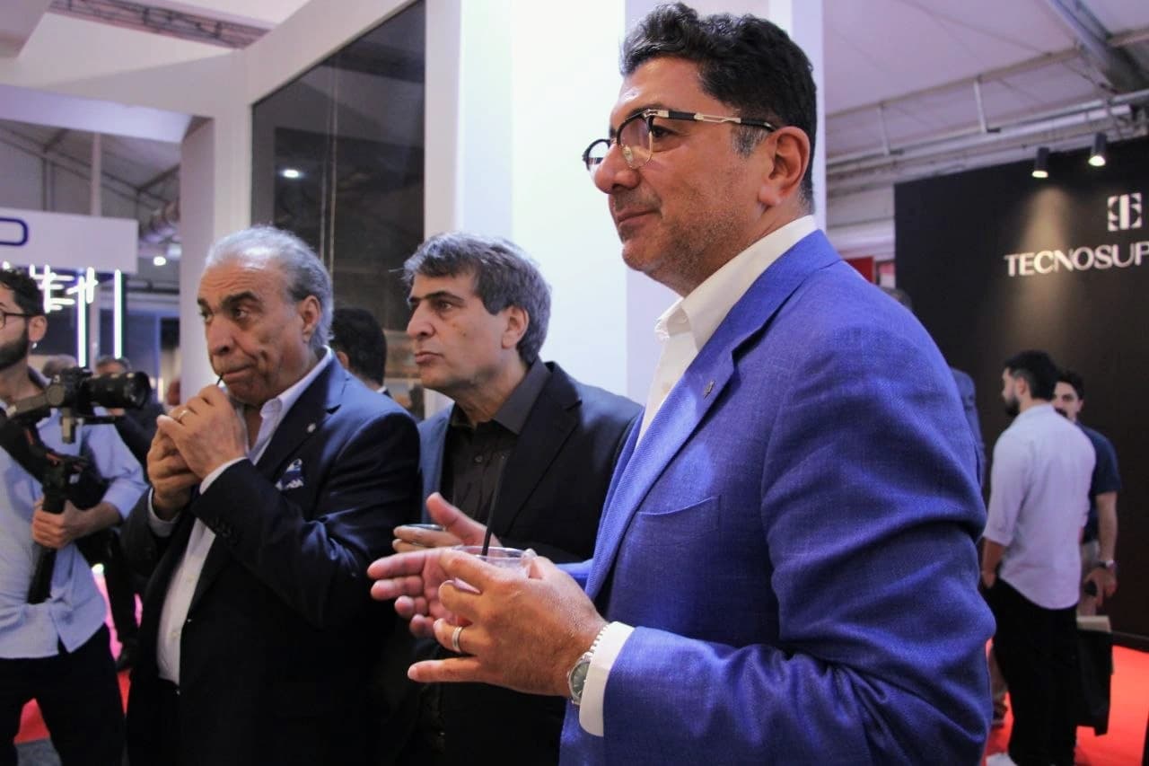 پژمان جوزی در جمع بازدیدکنندگان مقابل پنل‌های سنگی غرفه، در جریان دیدار از نمایشگاه صنعت ساختمان