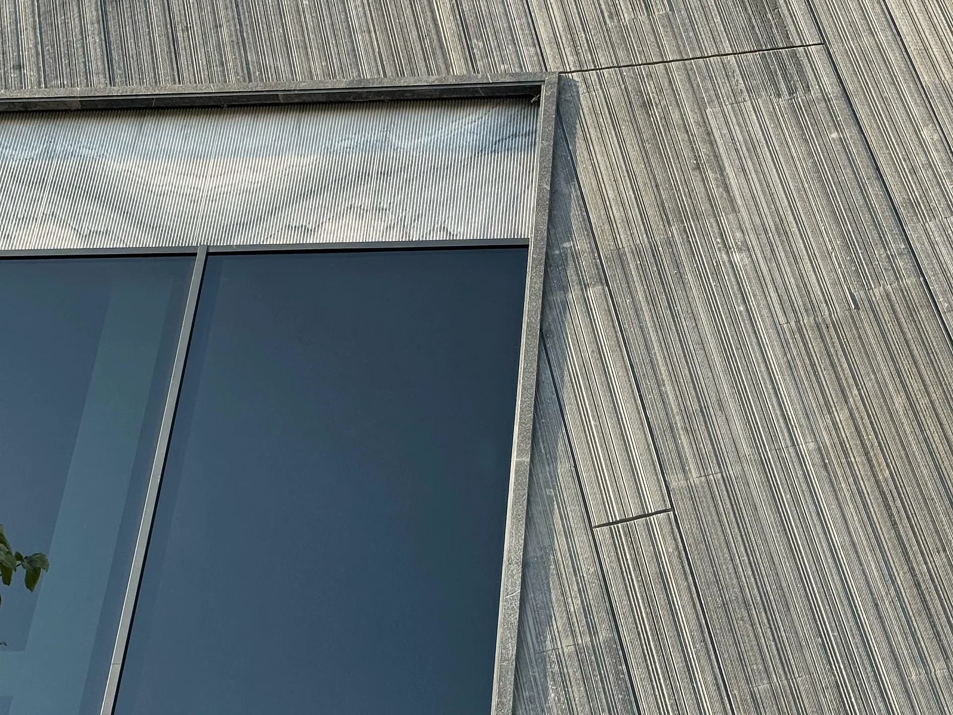 نمای نزدیک cladding سنگ طوسی شیاردار با جزئیات پنجره در پروژه مهندسی سنگ